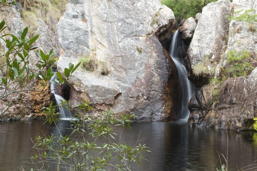 Twin waterfalls cascading over quartzite rock into the tree-fringed water of Tessa's Pool, Chimanimani