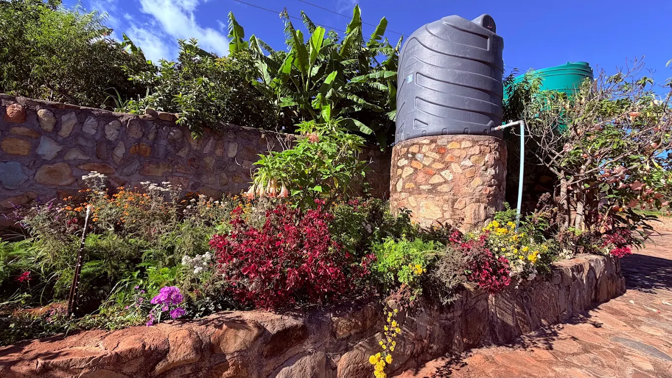 Terraced flower gardens at Eland Sanctuary with backup water storage tanks on stone plinths